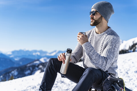 Deutschland, Bayern, Brauneck, Mann im Winter in den Bergen beim Pausieren, lizenzfreies Stockfoto