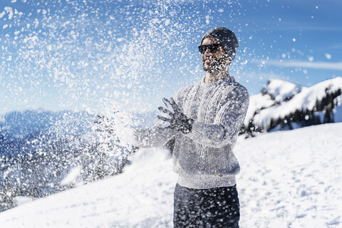 Deutschland, Bayern, Brauneck, Mann im Winter spielt mit Schnee in den Bergen, lizenzfreies Stockfoto