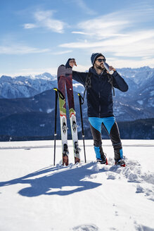 Deutschland, Bayern, Brauneck, Mann auf Skitour im Winter in den Bergen beim Pausieren - DIGF05956