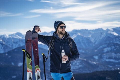 Deutschland, Bayern, Brauneck, Mann auf Skitour im Winter in den Bergen beim Pausieren, lizenzfreies Stockfoto
