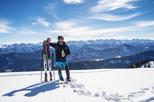 Deutschland, Bayern, Brauneck, Mann auf Skitour im Winter in den Bergen beim Pausieren - DIGF05958