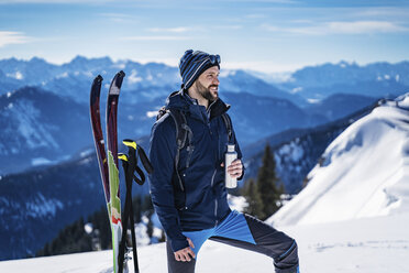 Deutschland, Bayern, Brauneck, Mann auf Skitour im Winter in den Bergen beim Pausieren - DIGF05960