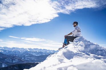Germany, Bavaria, Brauneck, man in winter sitting on mountaintop - DIGF05967