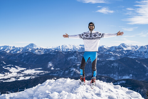 Deutschland, Bayern, Brauneck, glücklicher Mann im Winter auf einem Berggipfel stehend, lizenzfreies Stockfoto