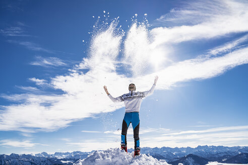 Germany, Bavaria, Brauneck, man in winter playing with snow in the mountains - DIGF05972