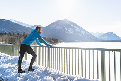 Deutschland, Bayern, sportlicher Mann im Winter auf Brücke stehend - DIGF05979