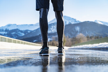 Deutschland, Bayern, Beine eines sportlichen Mannes, der auf einer Straße im Winter steht - DIGF05981