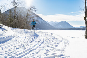 Deutschland, Bayern, sportlicher Mann läuft durch Schnee im Winter - DIGF05983