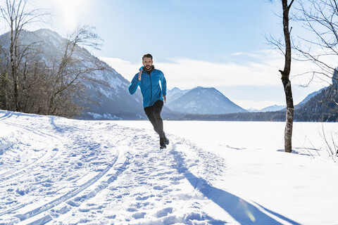 Deutschland, Bayern, sportlicher Mann läuft durch Schnee im Winter, lizenzfreies Stockfoto