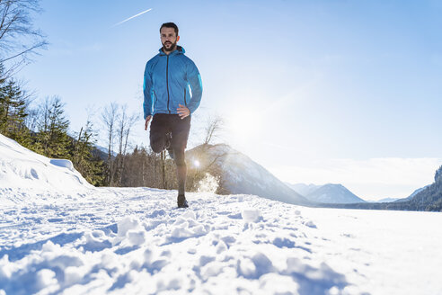 Deutschland, Bayern, sportlicher Mann läuft durch Schnee im Winter - DIGF05985