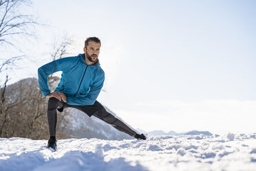 Germany, Bavaria, sportive man stretching in winter - DIGF05988