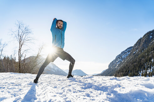 Deutschland, Bayern, sportlicher Mann beim Dehnen im Winter - DIGF05990