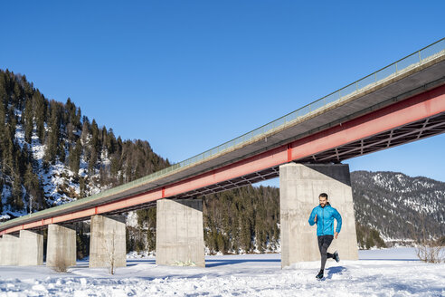 Deutschland, Bayern, sportlicher Mann beim Laufen an einer Brücke im Winter - DIGF05991