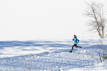 Deutschland, Bayern, sportlicher Mann läuft durch Schnee im Winter - DIGF05993