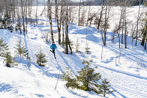 Deutschland, Bayern, sportlicher Mann läuft durch Schnee im Winter - DIGF05994