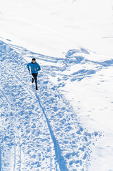 Deutschland, Bayern, sportlicher Mann läuft durch Schnee im Winter - DIGF05995