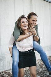 Portrait of laughing woman giving her friend a piggyback ride - HMEF00242