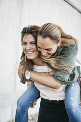 Portrait of laughing woman giving her friend a piggyback ride - HMEF00244