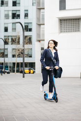 Active businesswoman riding scooter in the city - JRFF02734