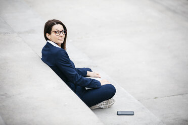 Portrait of businesswoman sitting outdoors on stairs with laptop - JRFF02745