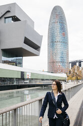 Spanien, Barcelona, Geschäftsfrau, die vor einem Bürogebäude in der Stadt spazieren geht - JRFF02758