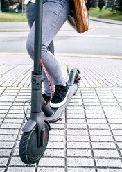 Close-up of young woman on electric scooter in the city - MGOF03953