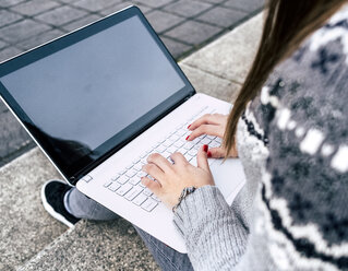 Close-up of woman sitting outdoors on stairs using laptop - MGOF03959