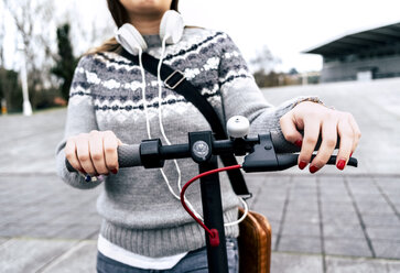 Nahaufnahme einer jungen Frau mit Elektroroller in der Stadt - MGOF03961