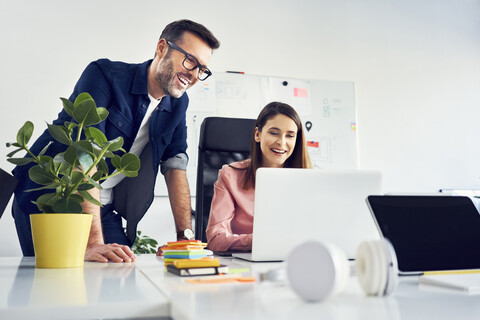 Two colleagues working together on laptop in office stock photo