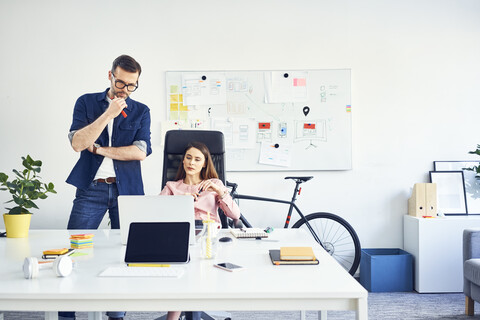 Two colleagues working together on laptop in office stock photo