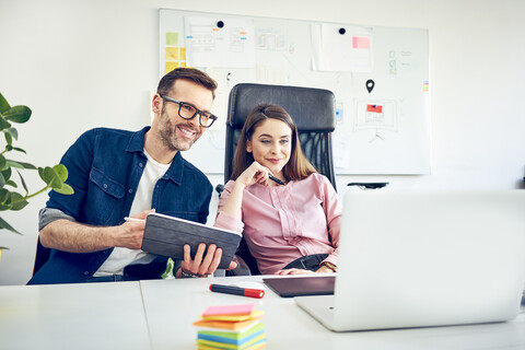 Two colleagues working together at desk in office stock photo