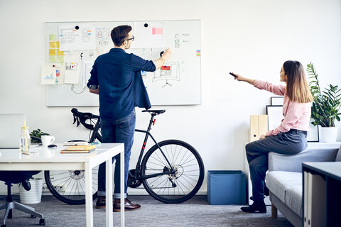 Zwei Kollegen diskutieren am Whiteboard im Büro, lizenzfreies Stockfoto