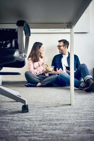 Two colleagues talking during lunch break in office stock photo