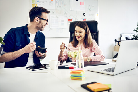 Two colleagues talking during lunch break in office stock photo