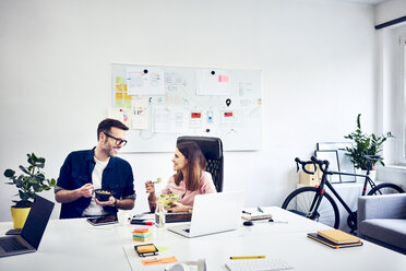 Two colleagues talking during lunch break in office - BSZF01008