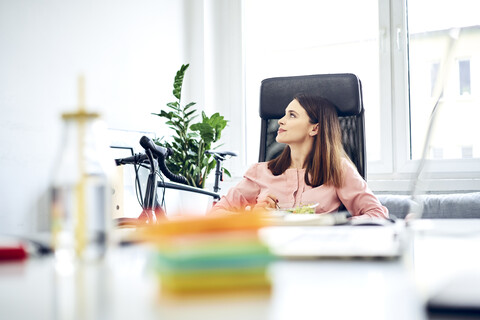 Businesswoman having lunch break in office sitting at desk stock photo