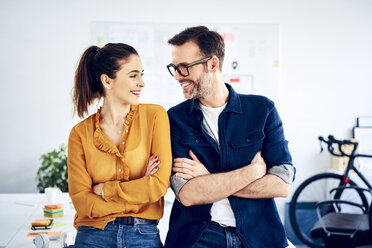 Two smiling colleagues in office facing each other - BSZF01023