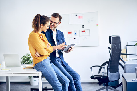 Zwei Kollegen mit Tablet treffen sich im Büro, lizenzfreies Stockfoto