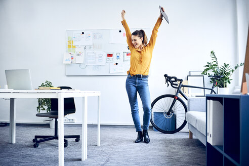 Happy young businesswoman cheering in office - BSZF01027