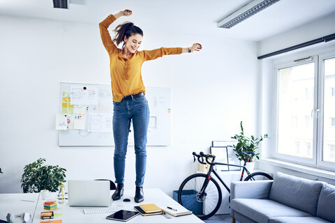 Glückliche junge Geschäftsfrau jubelt im Büro, lizenzfreies Stockfoto