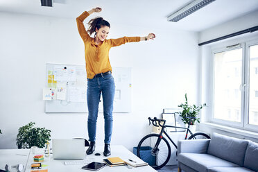Happy young businesswoman cheering in office - BSZF01030