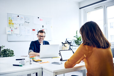 Two colleagues workin at desk in office - BSZF01045