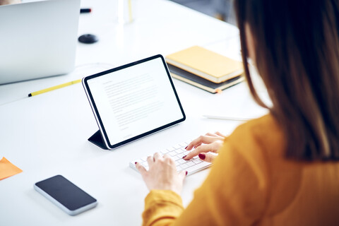 Close-up of businesswoman using tablet at desk in office stock photo