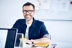 Porträt eines lässigen Geschäftsmannes bei der Arbeit am Schreibtisch im Büro - BSZF01049