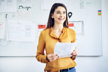 Smiling businesswoman with papers standing at whiteboard leading a presentation - BSZF01052