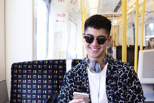 Young man using smartphone inside train - IGGF00879