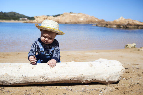 Spanien, Menorca, Kleinkind spielt mit Totholz am Strand - IGGF00896