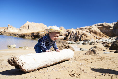 Spanien, Menorca, Kleinkind spielt mit Totholz am Strand - IGGF00897