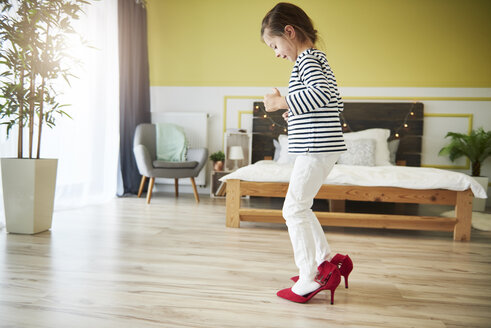 Kleines Mädchen verkleidet sich, trägt Mutters rote Stöckelschuhe - ABIF01174