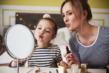 Mother and daughter applying make up together, using lipstick - ABIF01196